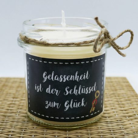Kerze in Glas mit Aufschrift: "Glück ist kostenlos, aber dennoch unbezahlbar".
