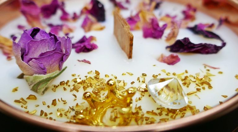 Kunstvolle Kerze mit getrockneten Blumen und goldenem Glitzer.